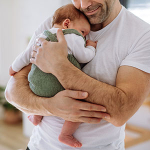 A man cradling a baby in his arms - Gomez Law PLLC