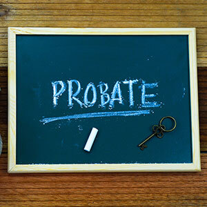 A blackboard with the word "PROBATE" written in chalk, with a piece of chalk and a key lying next to it - Gomez Law PLLC.